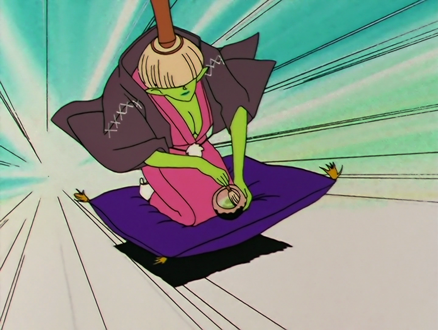 Chagama, a Daimon from Sailor Moon episode 104. She has green skin and wears a pink kimono with a grown layer over the top. She has a large tea whisk on her head, which obscures her eyes. She’s kneeling on a purple cushion which is rocketing along the ground at high speed, and she’s mixing up some matcha at the same time. She’s just really keen to do tea ceremony stuff, guys.